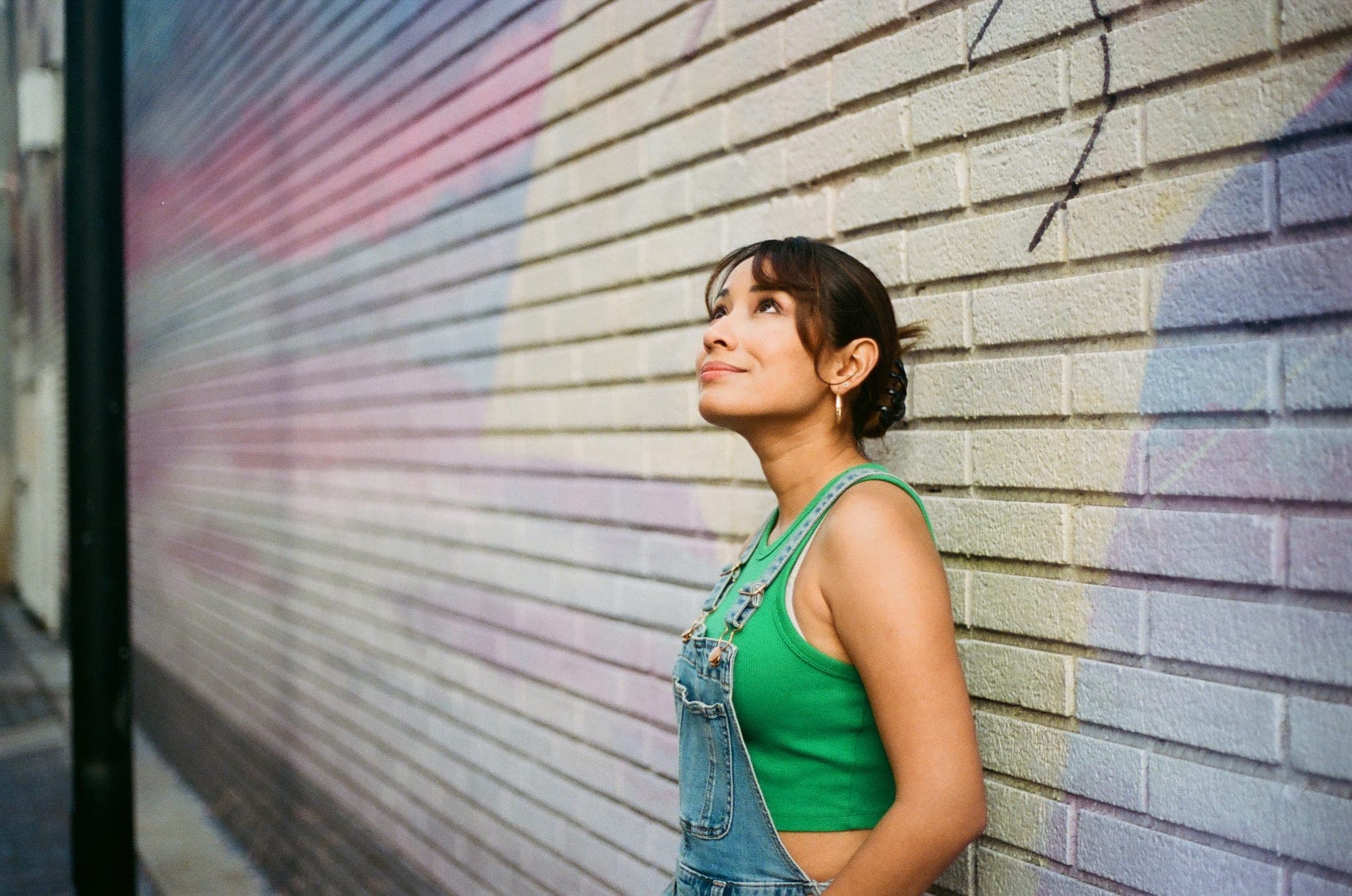 35mm film portrait of a woman in green against a painted brick mural wall