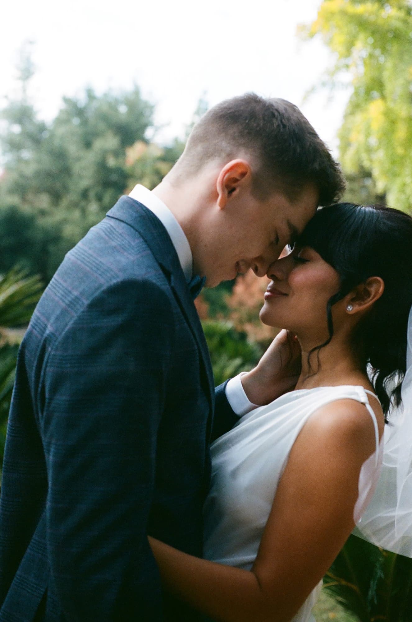 Bride and groom kissing in the garden, captured on 35mm film